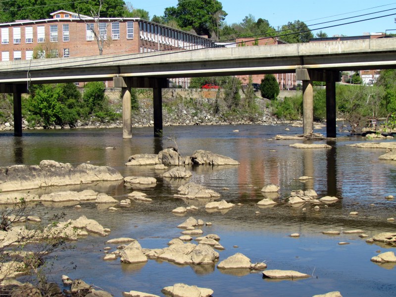 A rock filled river with a bridge over it.